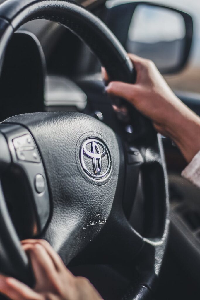 Hands gripping the wheel of a moving car, showcasing driving focus and control.